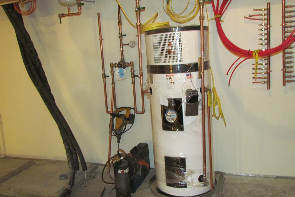 Chauffe-eau thermodynamique en local technique : ballon vertical surmonté de son groupe, raccordé en cuivre