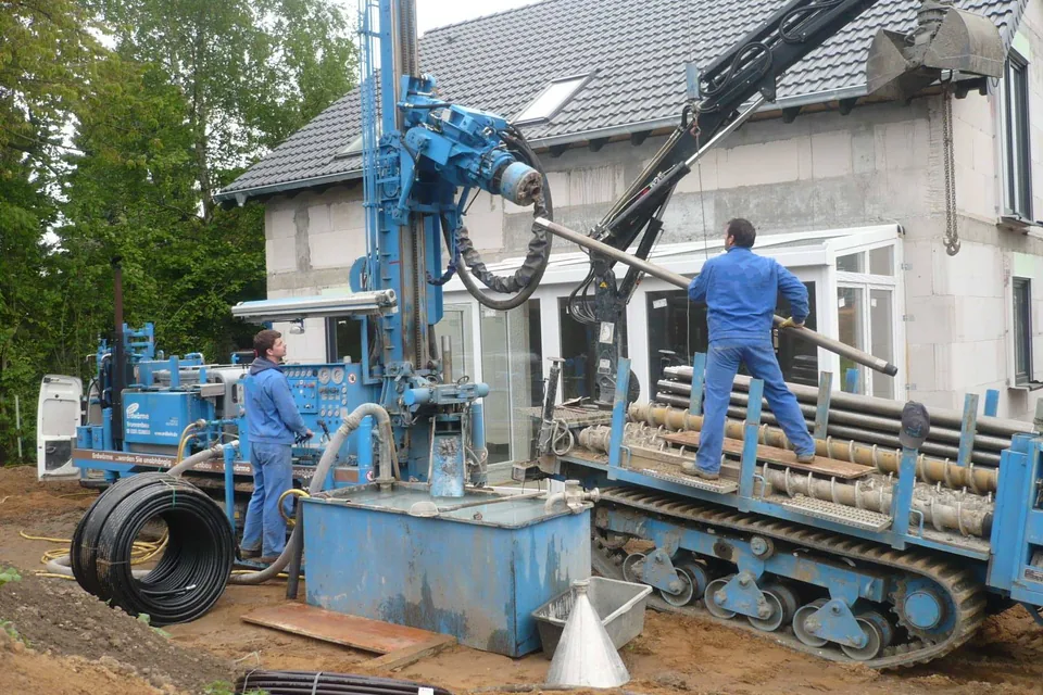 Foreuse sur chenilles en action contre une maison, mât dressé et opérateur au sol
